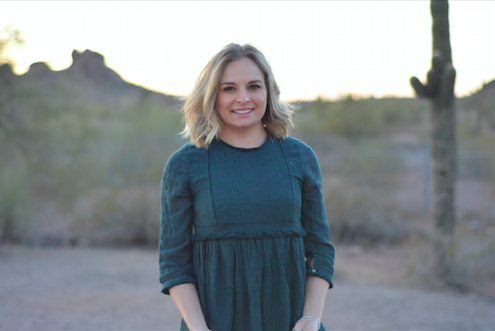 A young woman standing in front of a cactus.